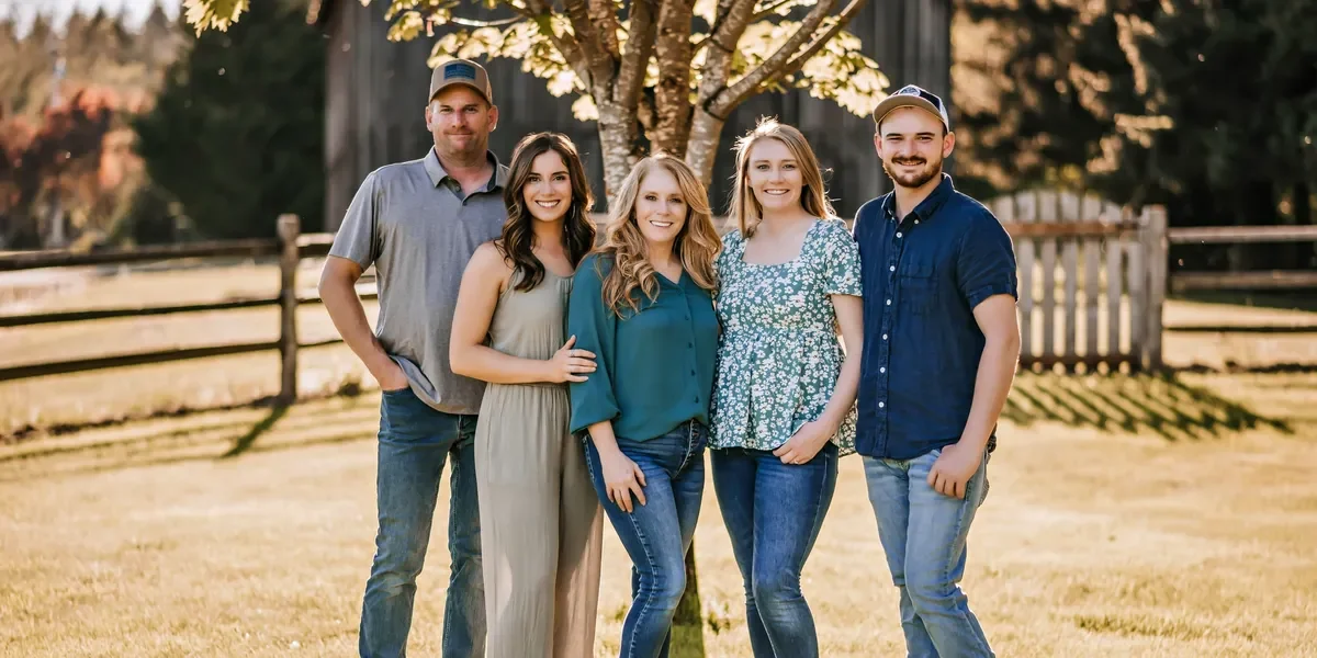 The Sass family standing together outdoors beneath a tree