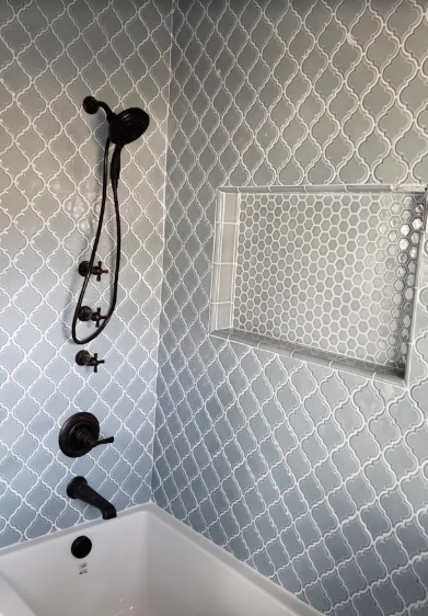 Bathtub and shower with gray patterned tile and matte black fittings